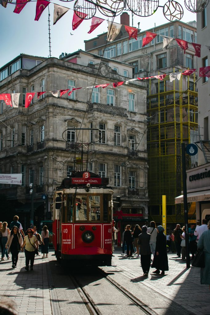 A red trolley car traveling down a street next to tall buildings